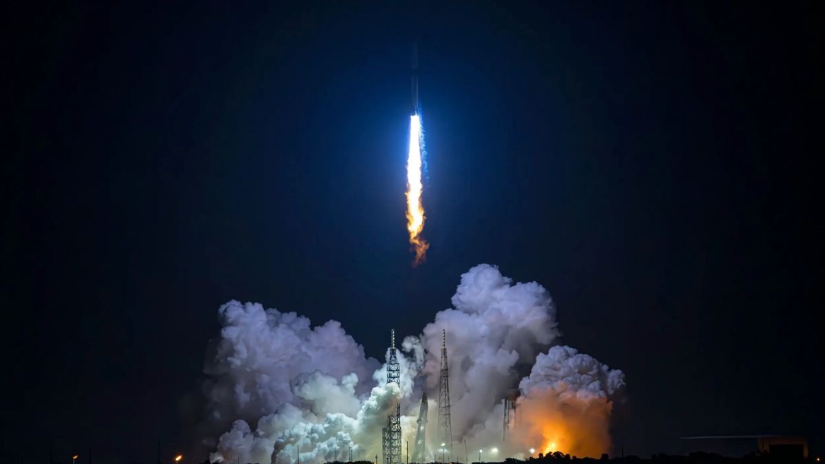 a large white rocket launches into a dark night sky