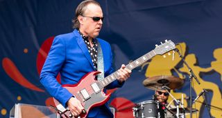 Joe Bonamassa wears shades, a bright blue suit and polka-dot short, as he plays a Gibson SG onstage during an opening slot for the Rolling Stones.