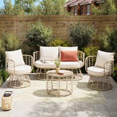 Rattan garden furniture set on a patio in front of olive trees