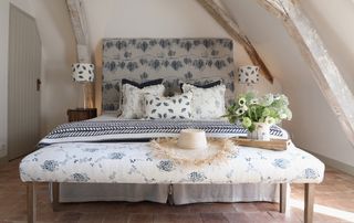 French country bedroom with bench and bed upholstered in blue and white fabric