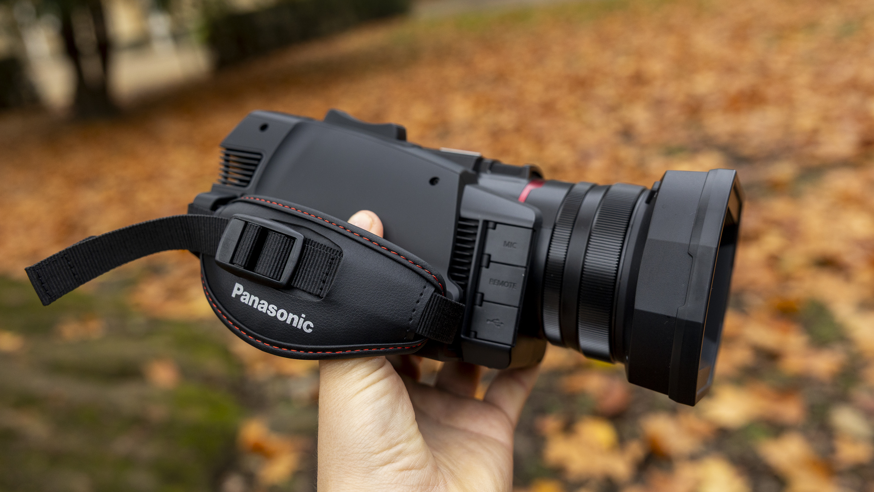 The Panasonic HC-X1200 camcorder held by a female photographer against an orange autumnal backdrop