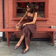 Woman wears polka dot dress, brown Alohas Rosalind ballet flats