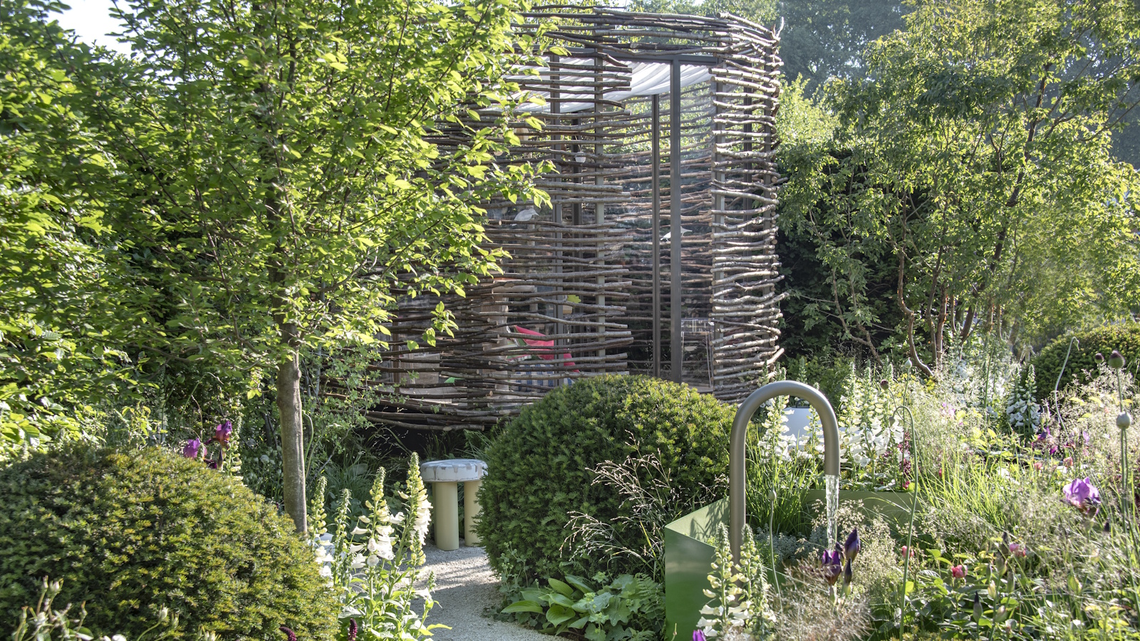 The Children With Cancer UK ‘A Place To Be...’ show garden at the 2025 RHS Chelsea Flower Show, designed by Tom Clarke and Ros Coutts-Harwood, with evergreen shrubs and dense perennial planting