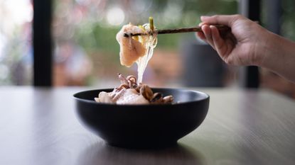 best ramen bowls: a ramen bowl with a hand using chopsticks to take food out of it