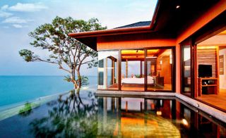Villa at the Habita overlooking ocean with infinity pool, large open sliding windows and one tree in front