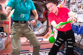 NASA astronaut Christina Koch squeezes a green slime blob out of a bag on board the International Space Station.