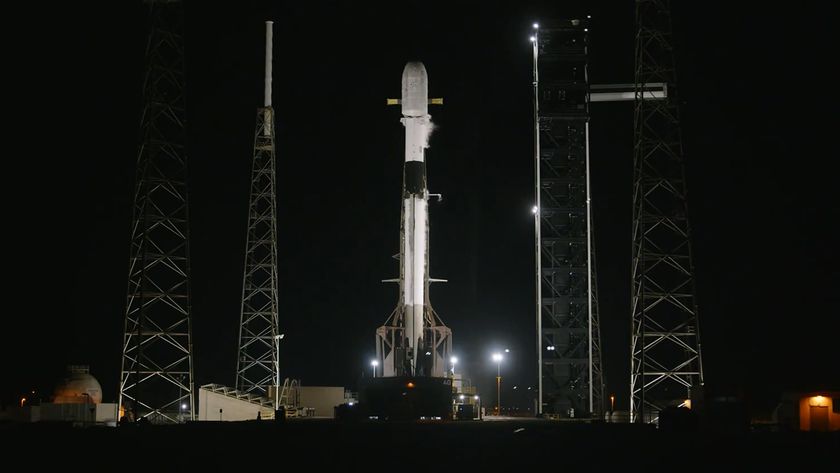 A SpaceX Falcon 9 rocket standing fully fueled on a launch pad at night.