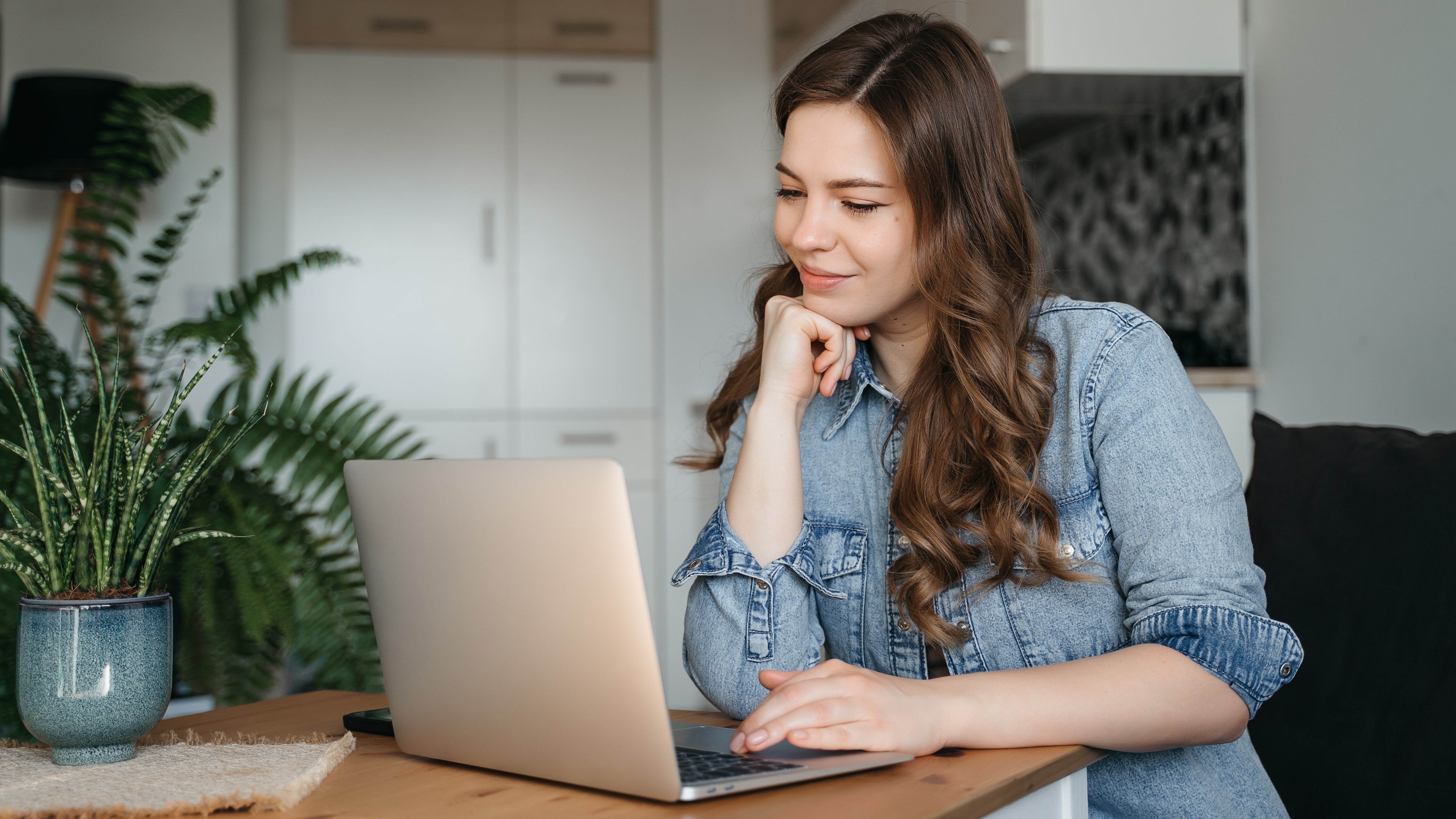 Mujer sonriendo mientras usa MacBook en el escritorio.