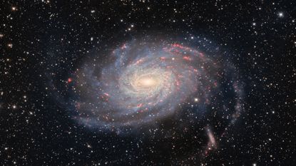 A photo of a spiral galaxy with blue and red streaks