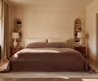 Bedroom with large double bed in brown linen with inbuilt arched shelving units