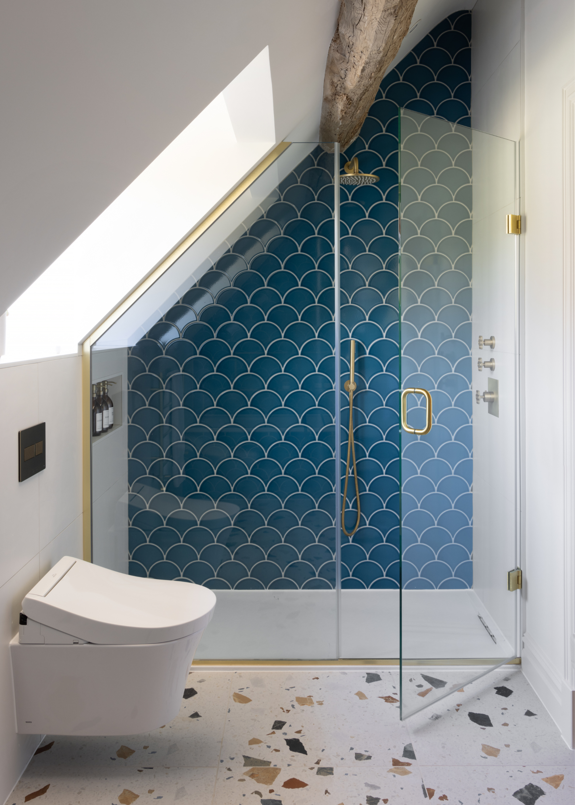 small loft bathroom with a blue tiled shower and terrazzo tiled floor