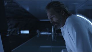 Screenshot from the movie Tron: Legacy. An older man wearing a white long-sleeved shirt is peering down into the darkness.