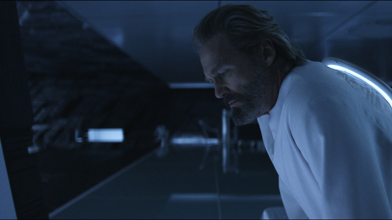 Screenshot from the movie Tron: Legacy. An older man wearing a white long-sleeved shirt is peering down into the darkness.