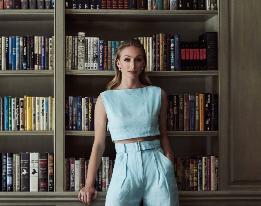 a woman in blue standing in front of a bookshelf