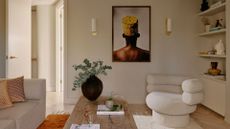 A living room with a sofa chair, a couch, a wood coffee table, framed art and shelves