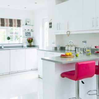 white kitchen with white cabinet and pink chairs.