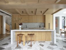 A kitchen with tile flooring and wooden island and cabinets