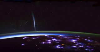 Comet Lovejoy points to the green sheen of airglow in Earth's atmosphere and the purple points of electricity across Earth's surface.