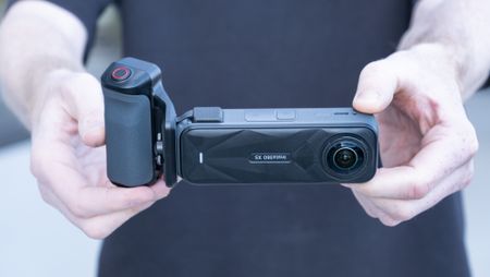 Insta360 X5 Photography Grip attached to the camera, in the hand