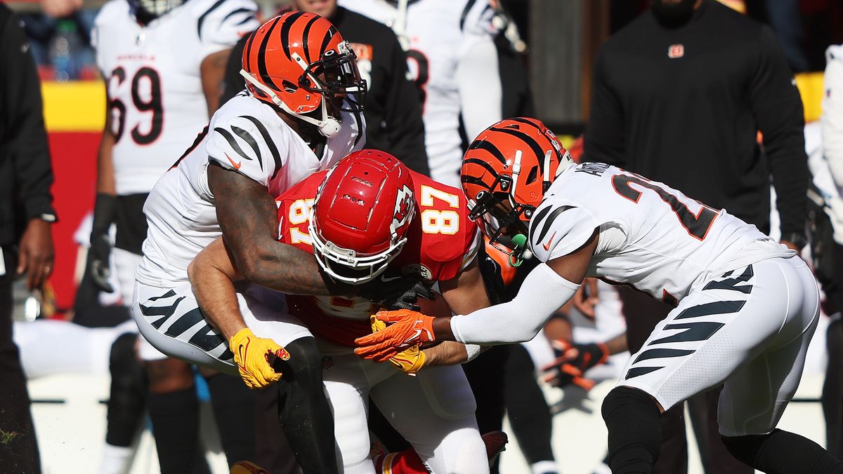 Travis Kelce #87 of the Kansas City Chiefs runs with the ball as Germaine Pratt #57 and Chidobe Awuzie #22 of the Cincinnati Bengals defend in the AFC Championship Game at Arrowhead Stadium on January 30, 2022 in Kansas City, Missouri.