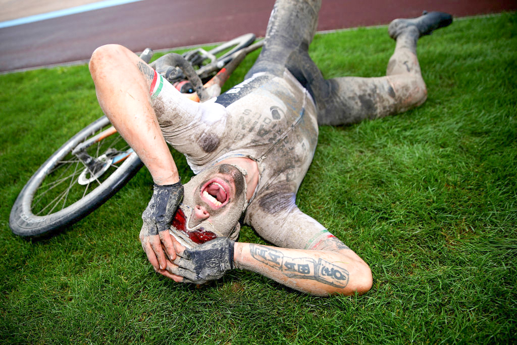 A muddy Sonny Colbrelli shouts and celebrates lying on the infield after winning the 2021 Paris-Roubaix