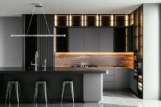 A black kitchen with lighting above the island