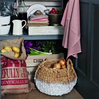 Harvested onions, spring onions and potatoes in woven basket, hessian sack and wooden crates