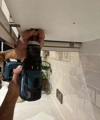 Drilling hooks into underside of a kitchen cabinet