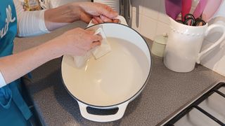 Dutch oven being wiped clean with kitchen towel