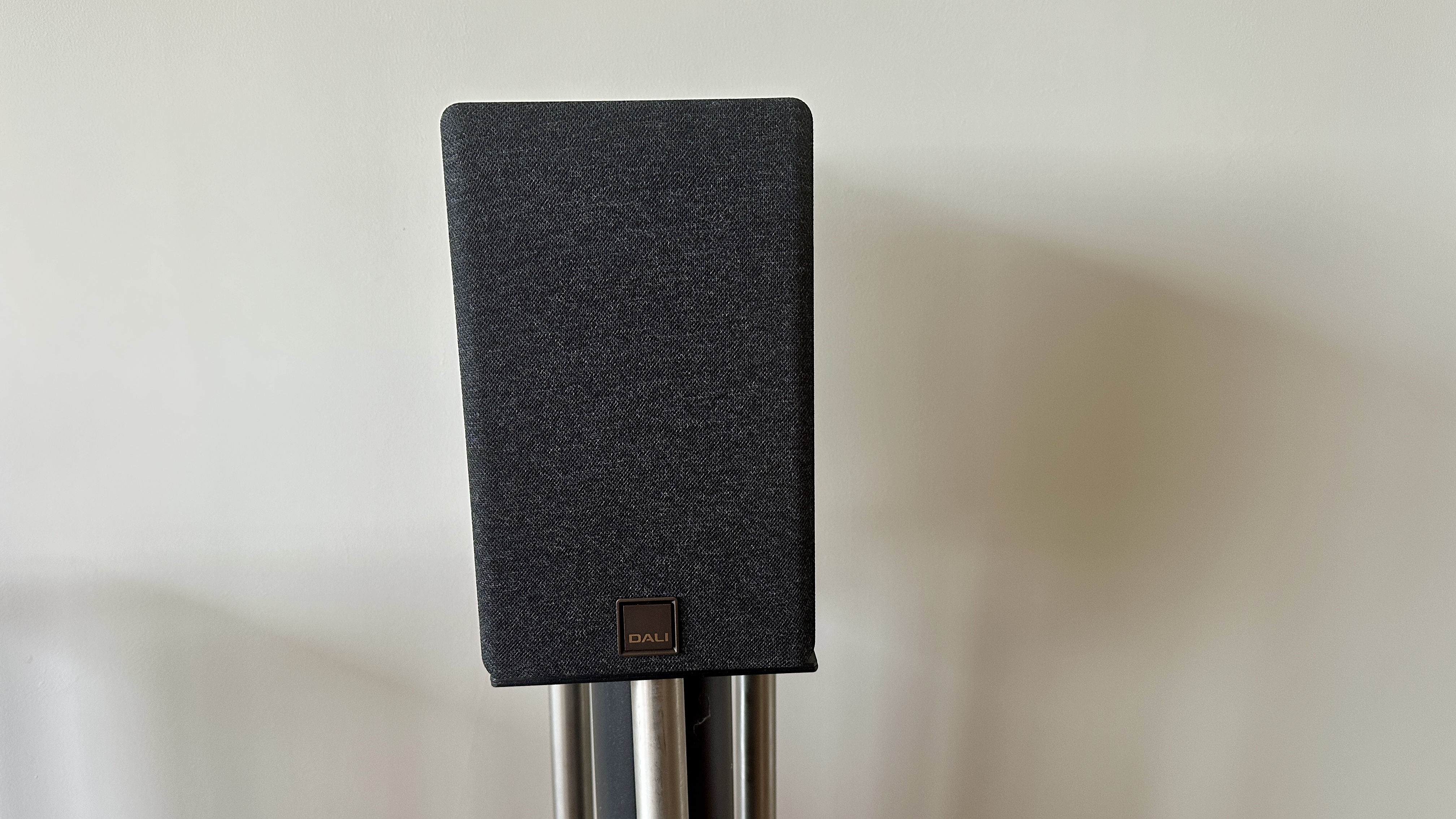 Magnetically attached grille of the Dali Kupid bookshelf speakers, placed on a speaker stand.