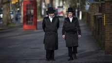 Jewish men walk along the street in the Stamford Hill area 