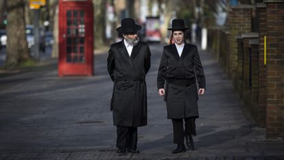 Jewish men walk along the street in the Stamford Hill area 