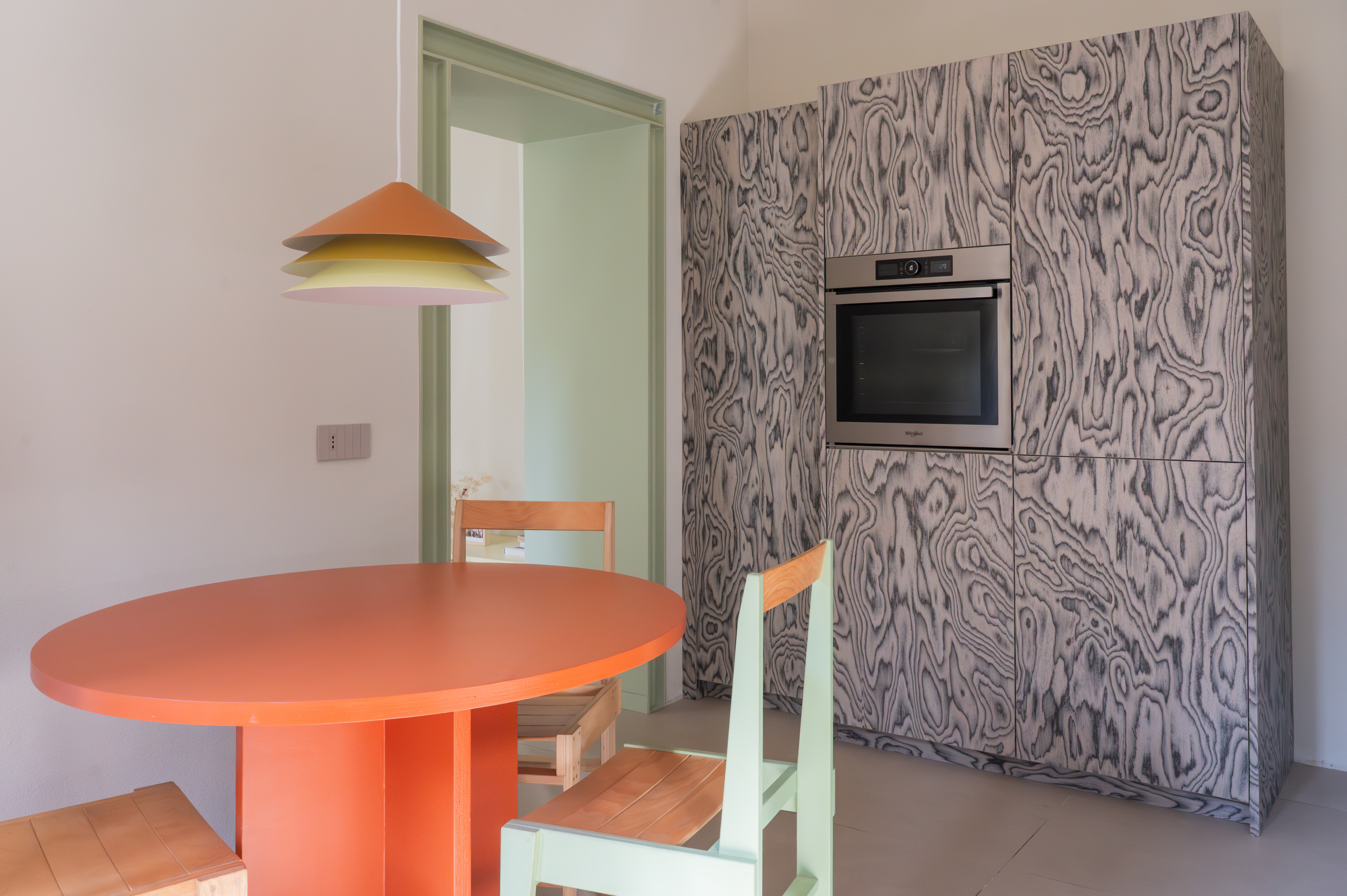 a colorful kitchen with mint and orange accents, and patterned wooden veneer cabinets
