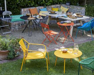 A set of colorful outdoor bistro patio tables and chairs in external backyard area with cooking station