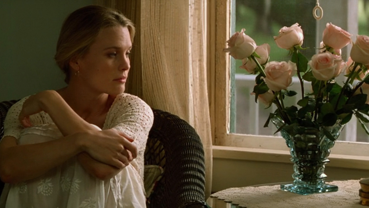 Robin Wright sitting by a window, looking at some flowers in Forrest Gump