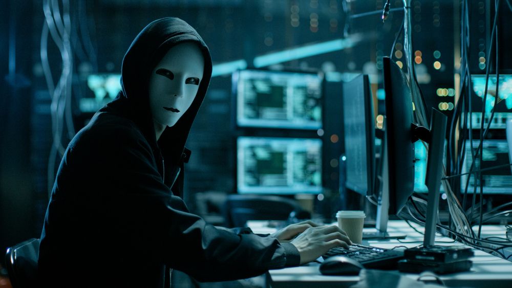 Hacker wearing white mask stares at camera