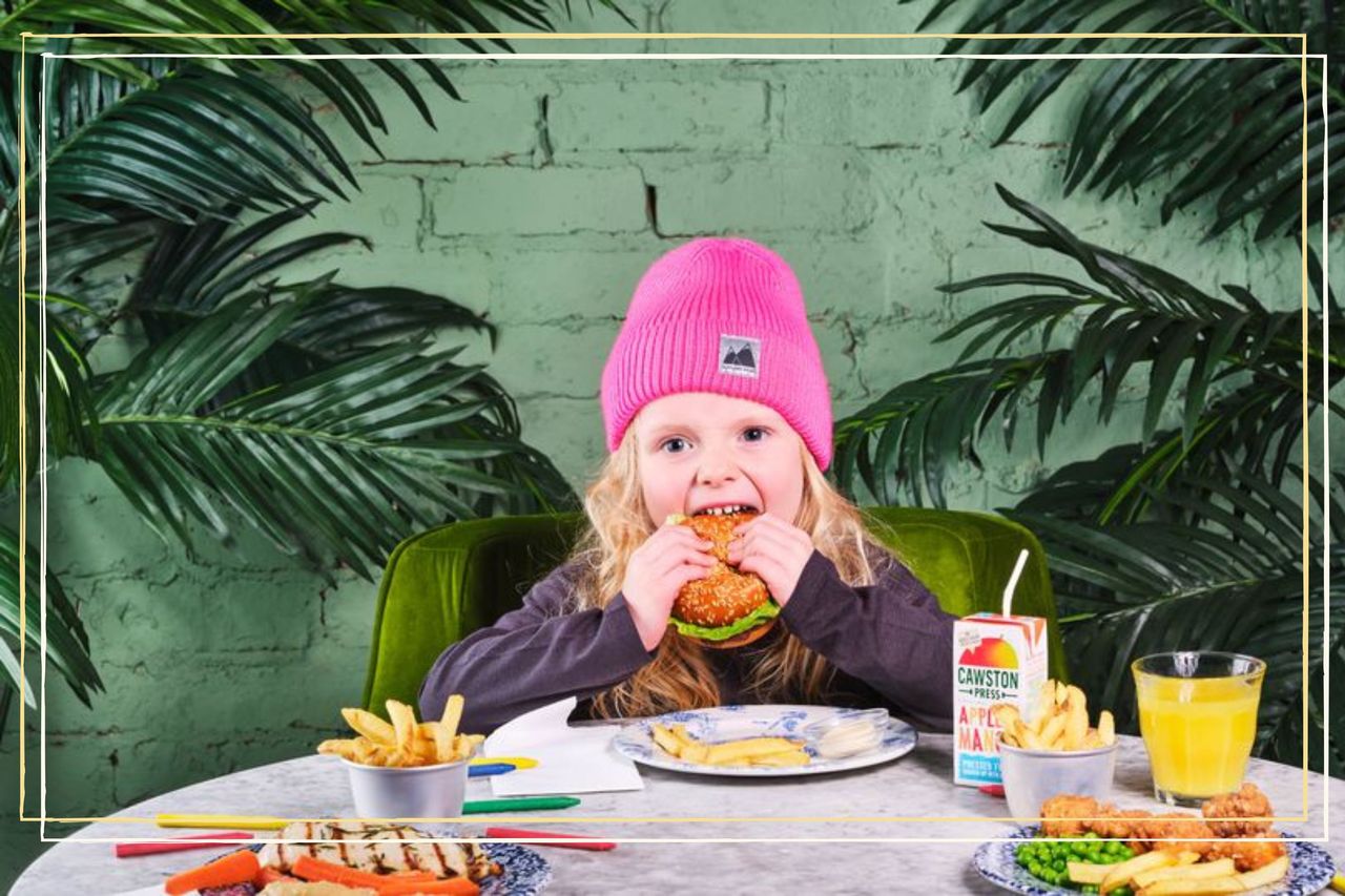 A child sat at a table eating a burger