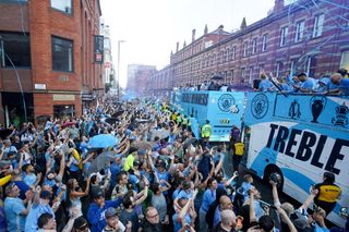 Manchester City players celebrate their treble triumph with fans on a bus parade through the city in June 2023.