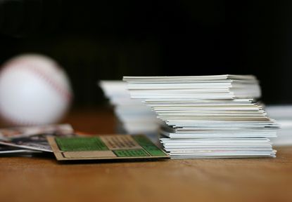 "Collection of baseball cards and baseball on old wooden table.Shallow dof, focus on stack of cards baseball in background is out of focus."