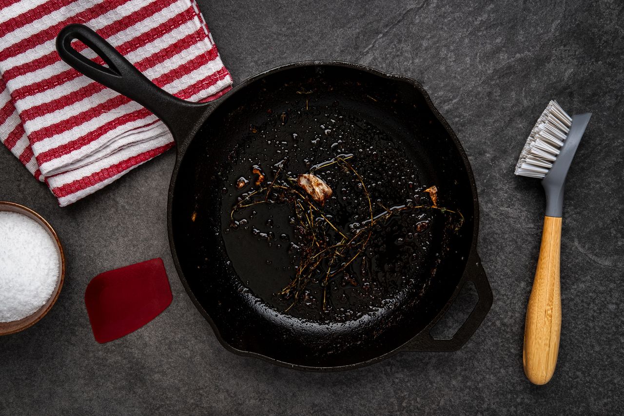 A picture showing how to clean a cast iron skillet with a brush and salt