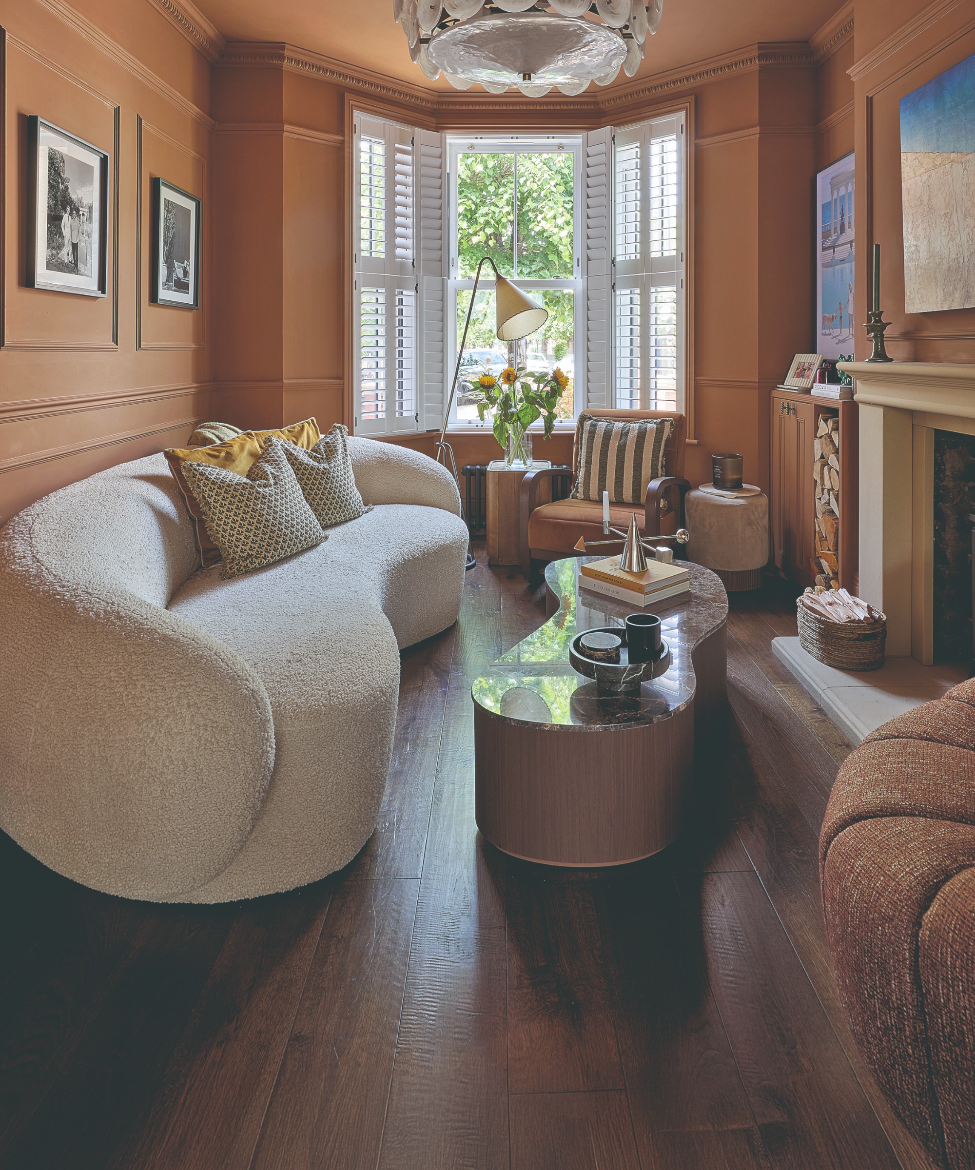 A colour-drenched living room with a curved white boucle sofa, a curved coffee table and two armchairs facing it