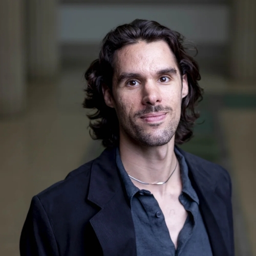 Image of a man wearing a navy shirt and black blazer