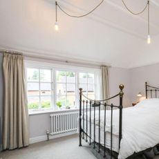 bedroom with metal bed and casement windows with thermal curtains