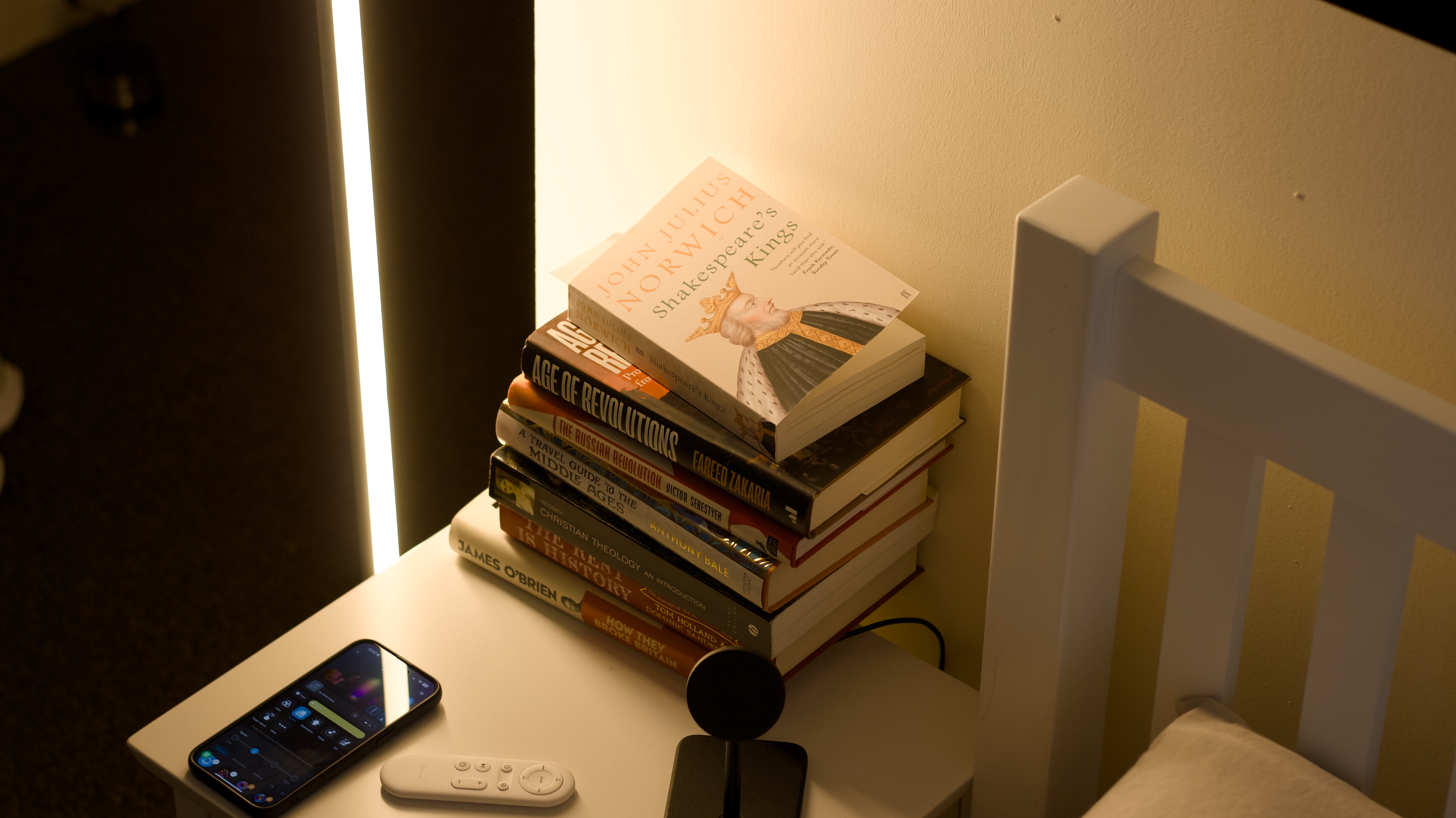 Govee Floor Lamp Pro illuminated white beside nightstand with books