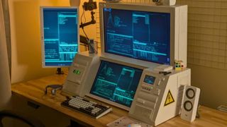 A three screen setup is seen on a desk. These screens are encased in an off-white shell designed to look retro and bring to mind classic CRT housing.