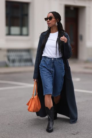 woman wearing white t-shirt, coat, bermuda shorts, and cowboy boots