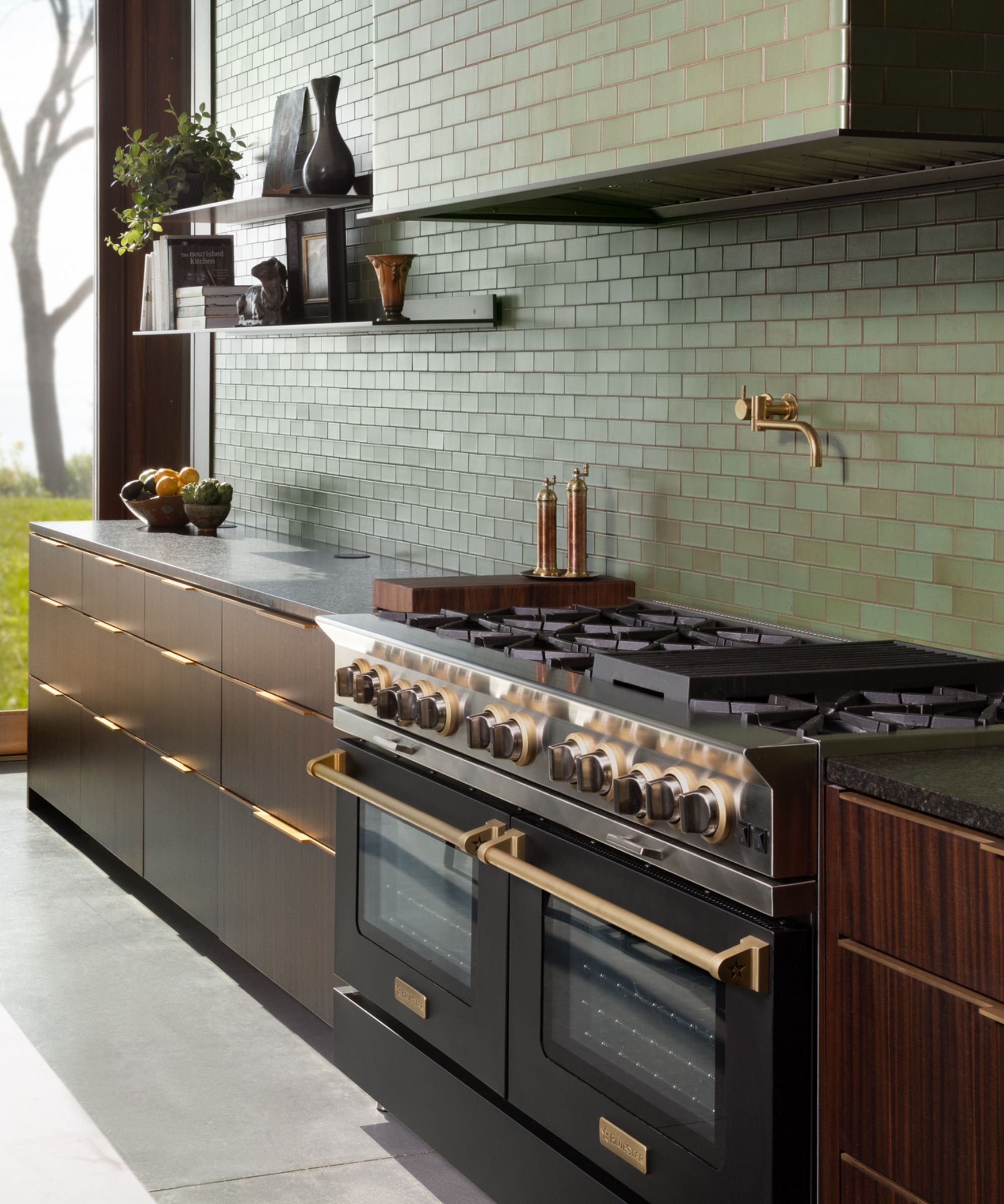 A green subway tiled kitchen with dark wooden cabinets and a double black stove.