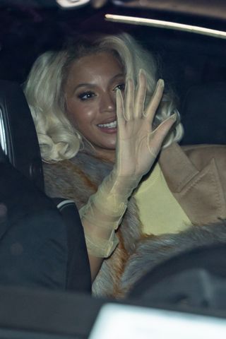 Beyoncé waving in sheer mesh gloves as she arrives at the ceremony.