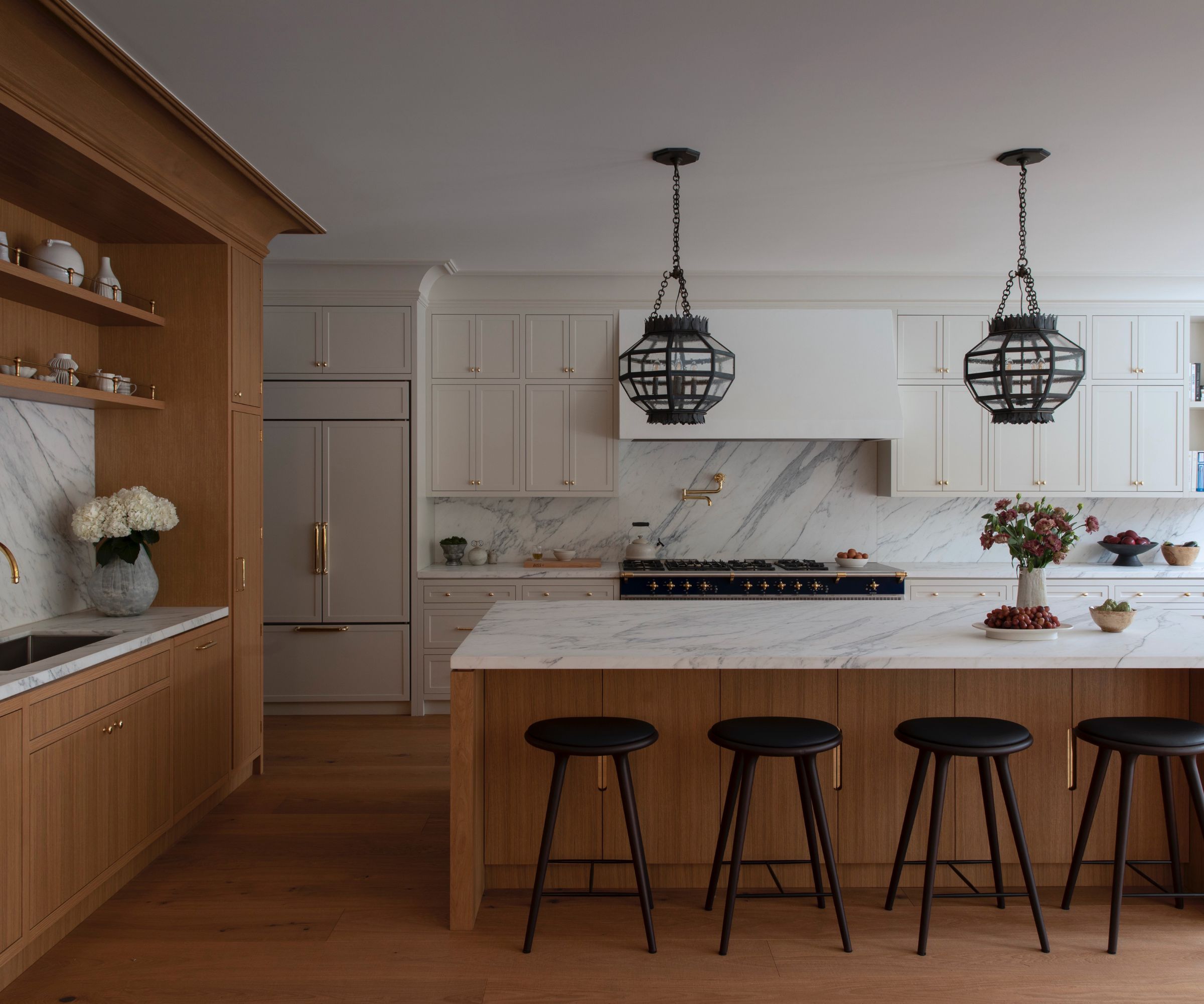 A large kitchen with a wooden island and sink area, paired with white cabinetry on the back wall