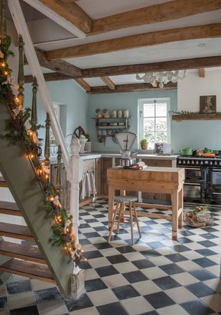 kitchen with blue walls and black aga and brown cabinets with stairs and christmas decorations